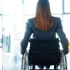 rear view of a businesswoman sitting in a wheelchair in an office
