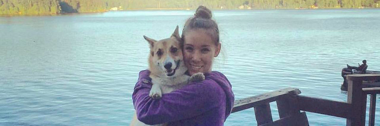 Young woman lifts up and hugs her dog