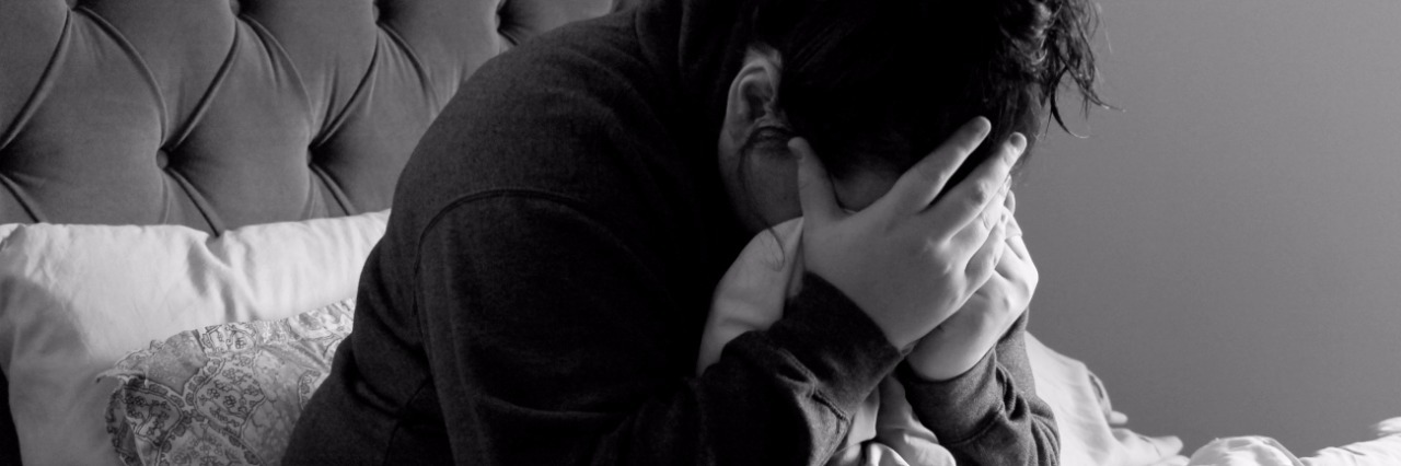 What It's Like Having Endometriosis black and white photo of woman sitting on bed holding her head