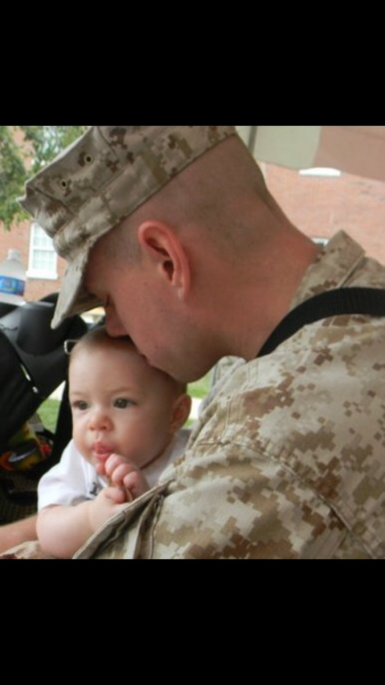 a man in the army kissing his baby