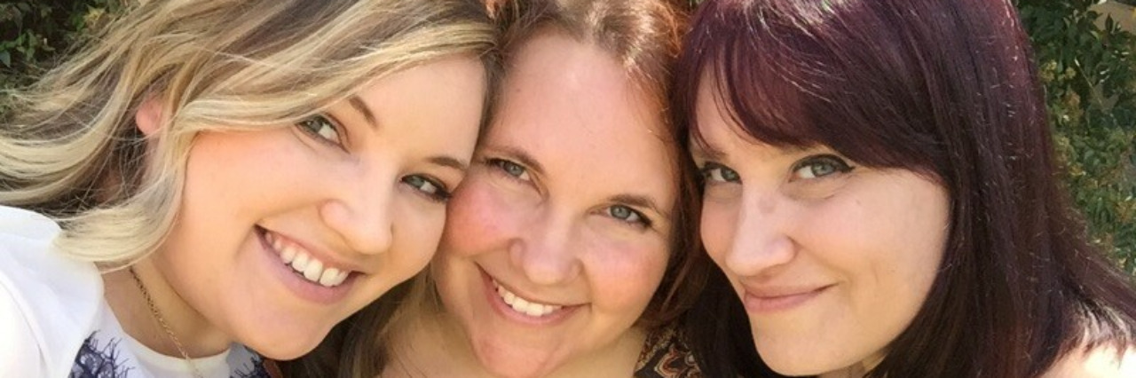 Three woman embracing and smiling for the camera.