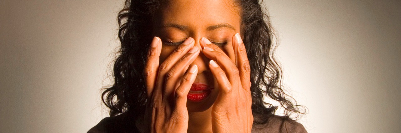 Migraine Symptoms You Can't See woman holding hands on face with migraine