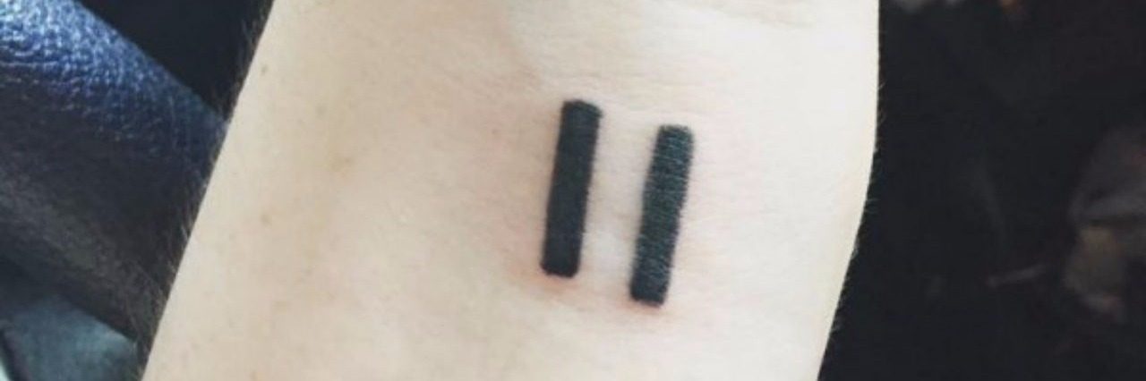 a tattoo of a pause sign on a persons wrist