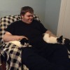 young man sitting in chair with two cats