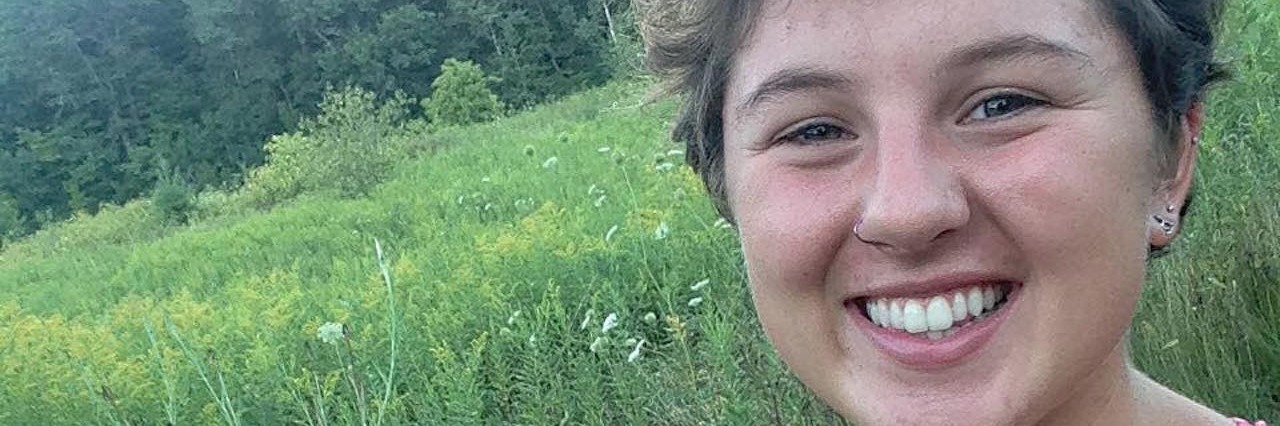 Finding Joy and Positivity in Life With Ehlers-Danlos Syndrome young woman in pink tank top smiling in green field