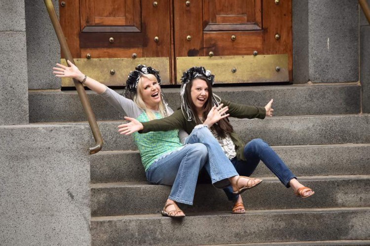 Melissa and her friend smiling while sitting on stairs