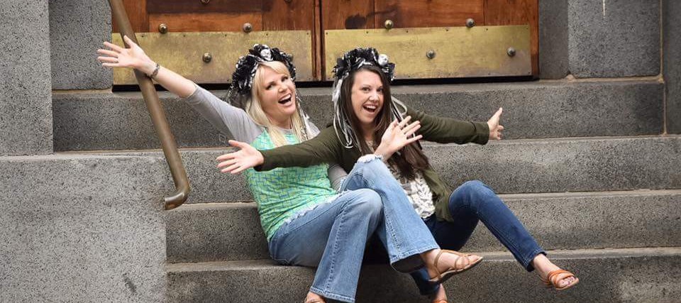 Melissa and her friend smiling while sitting on stairs