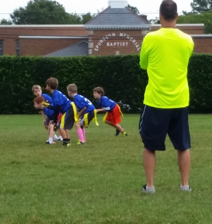 coach watching boys play a game on field