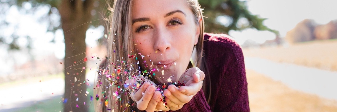 A woman blowing glitter out of her hands