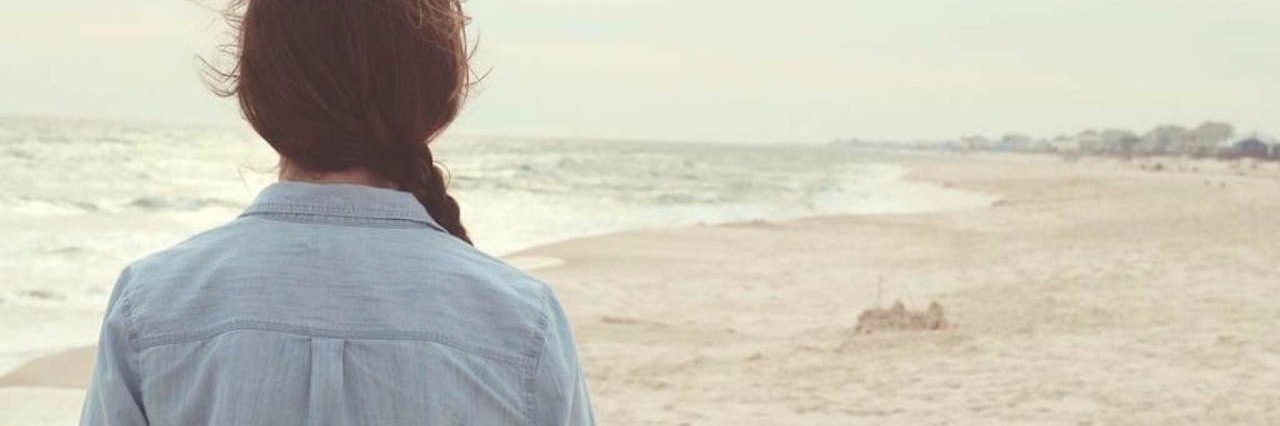 Reality of Life as a Young Woman With Chronic Lyme Disease woman in jean jacket walking on the beach