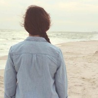 woman in jean jacket walking on the beach