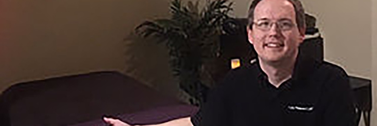 Being Legally Blind Helps Me Be a Better Massage Therapist Kyle standing next to his massage table.