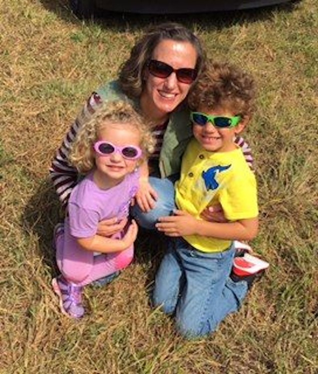 A mom and her two kids in sunglasses outside