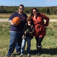 mom dad and son picking pumpkins
