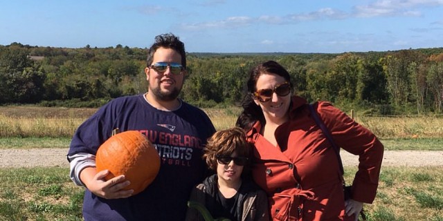 mom dad and son picking pumpkins