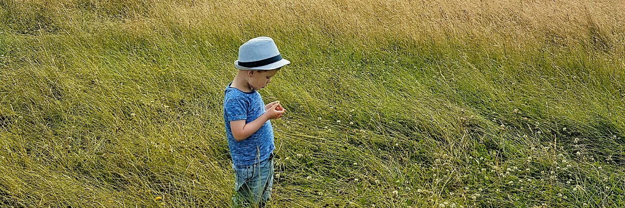 Why You Shouldn't Say Sorry About My Son's Autism The author's son in a grassy field under a cloudy blue sky