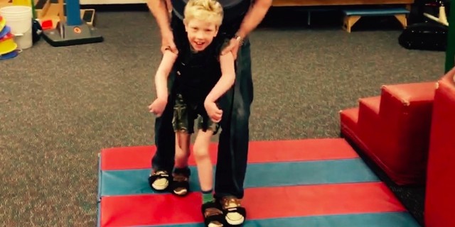 Gavin taking steps in physical therapy