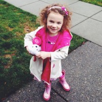 Girl wearing a headband and pink dress with pink rainboots