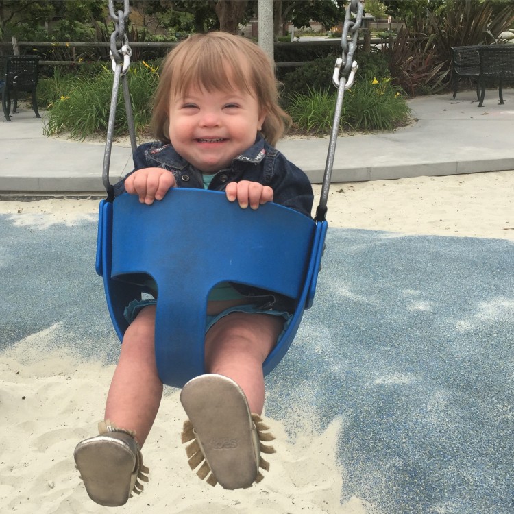 a little girl sitting in a baby swing and smiling