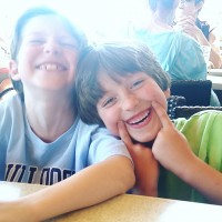 two kids smiling while sitting at table together