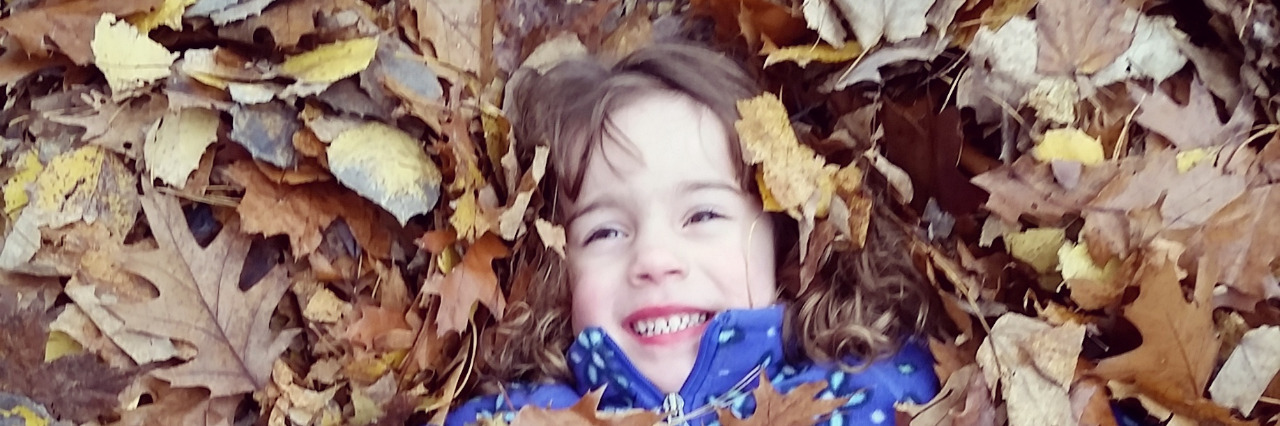 A little girl playing in leaves