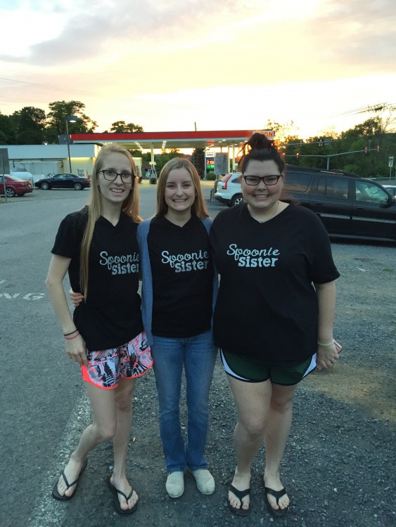 three girls standing in parking lot at sunset