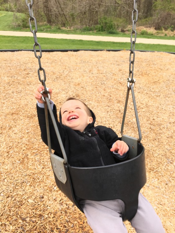 boy sitting in baby swing at park