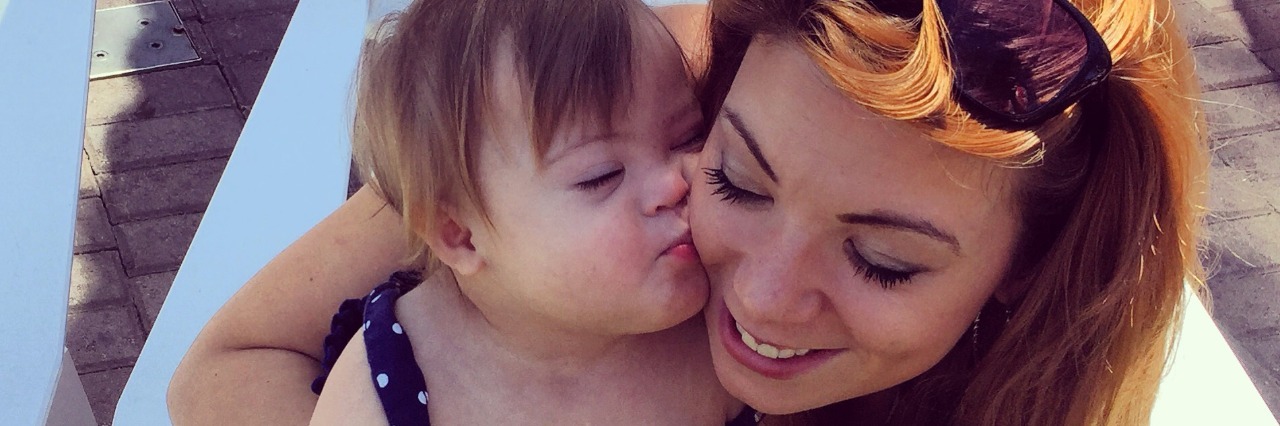 Advice for When You Compare Your Child With Down Syndrome to Others a mom holding her baby daughter in her lap