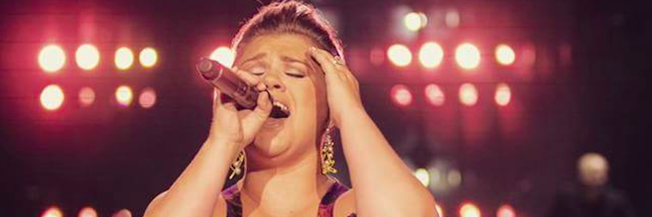 Kelly Clarkson Songs That Have Helped Me In My Depression and Anxiety A female singer in a dress performing on stage