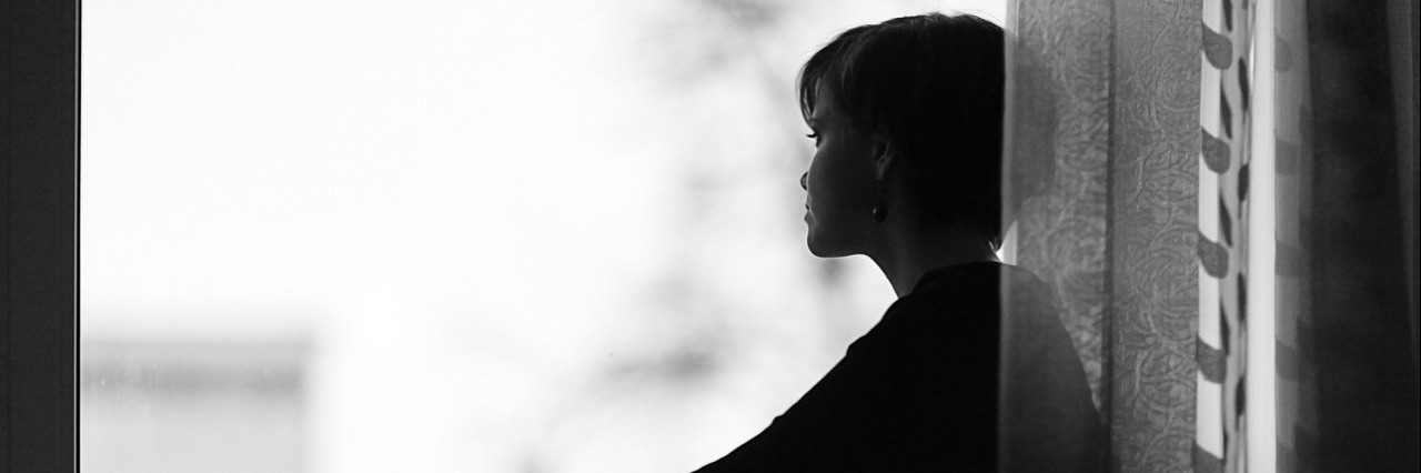 Woman’s Grief After a Miscarriage Doesn’t Fit Any Category woman on the windowsill looking out the window