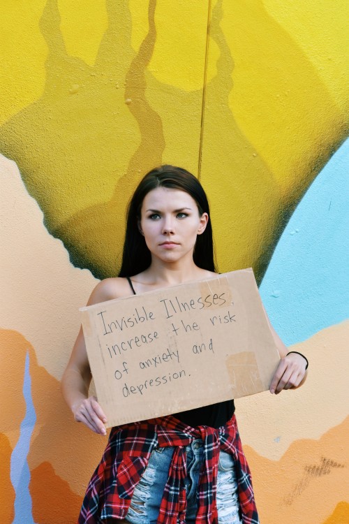 a woman holds a sign that says invisible illnesses increase the risk of anxiety and depression