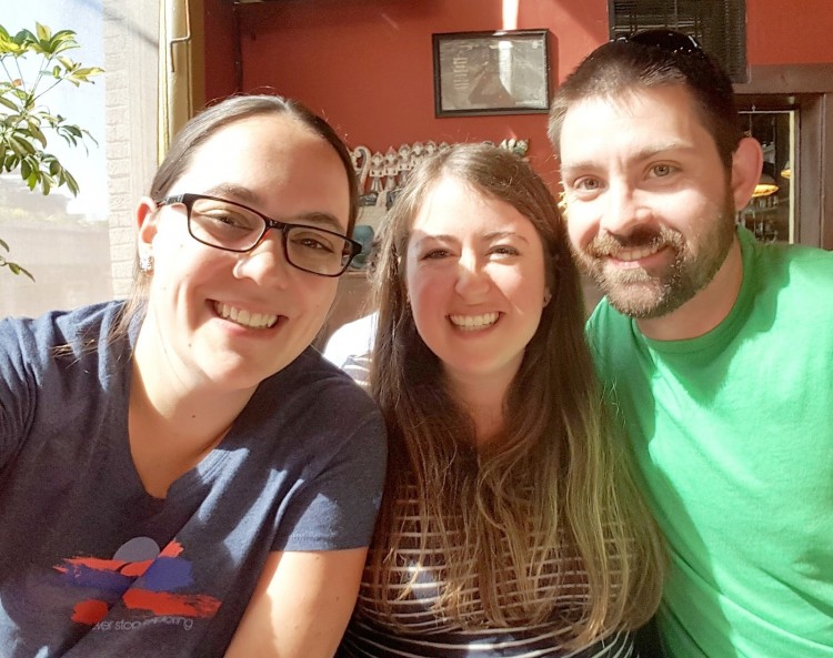 Two women and a man sitting and smiling for camera