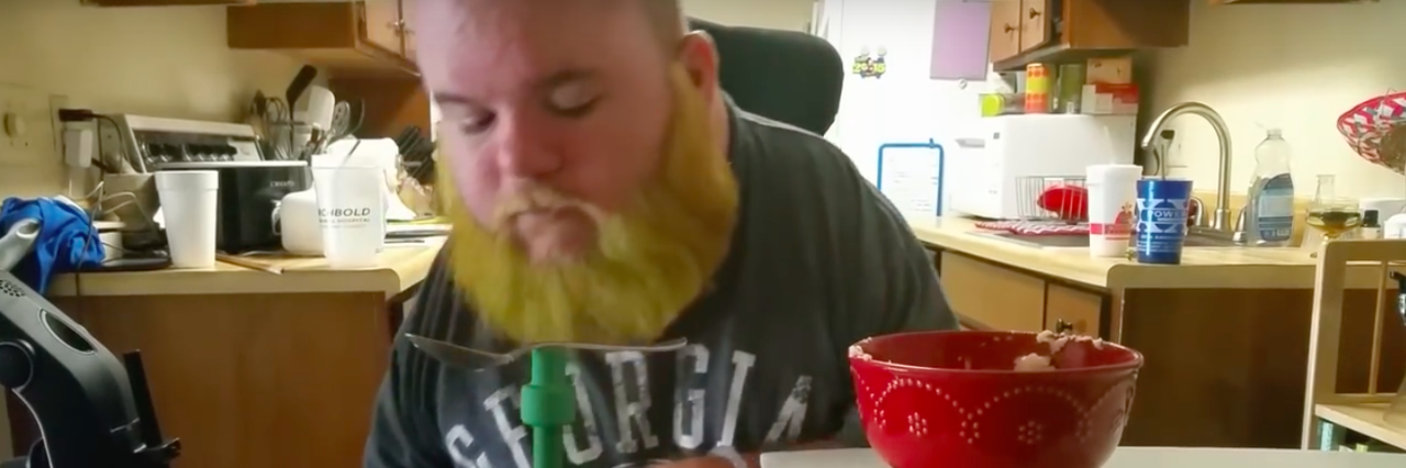 Ryan Hines Creates Bear Paw Self-Feeding Device for Disabled People Still image of man using Bear Paw to eat