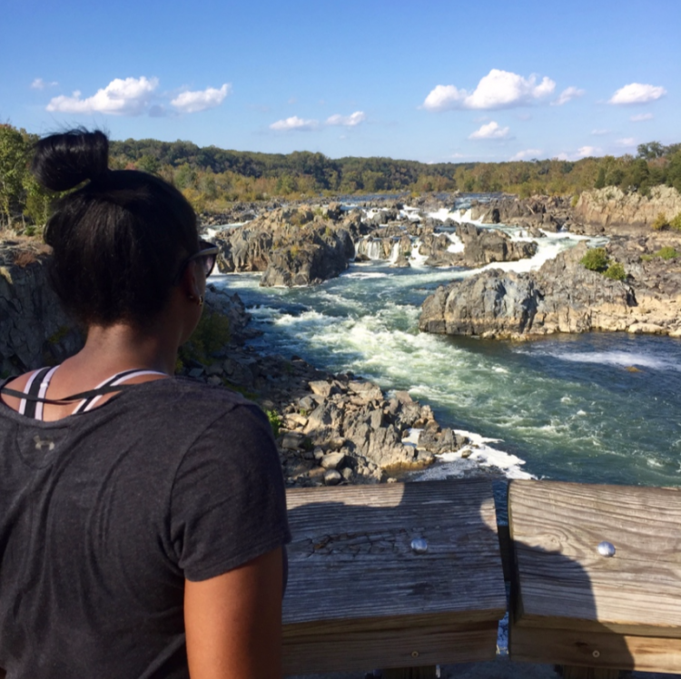 woman standing next to a wooden railing overlooking a river