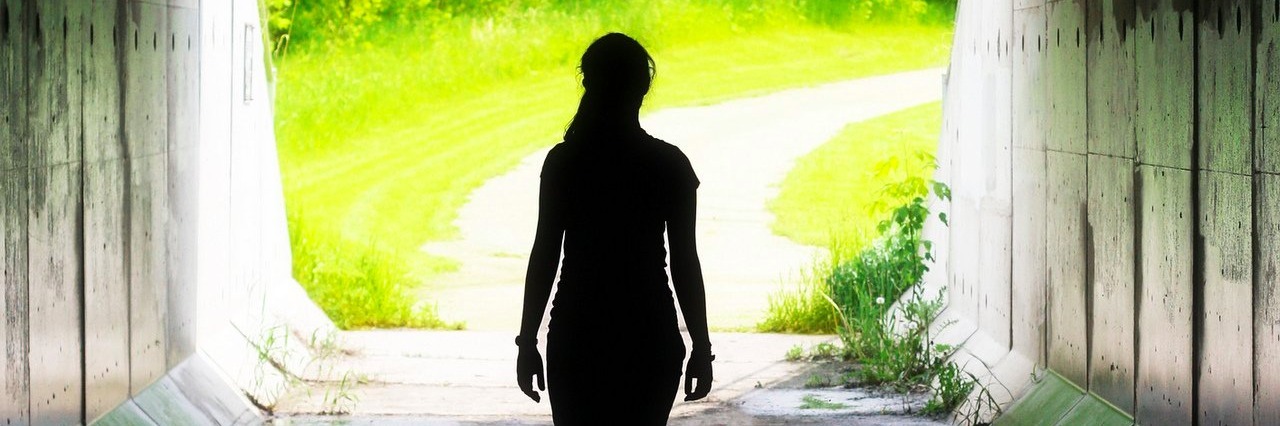 woman walking towards the light at the end of a tunnel