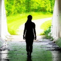 woman walking towards the light at the end of a tunnel
