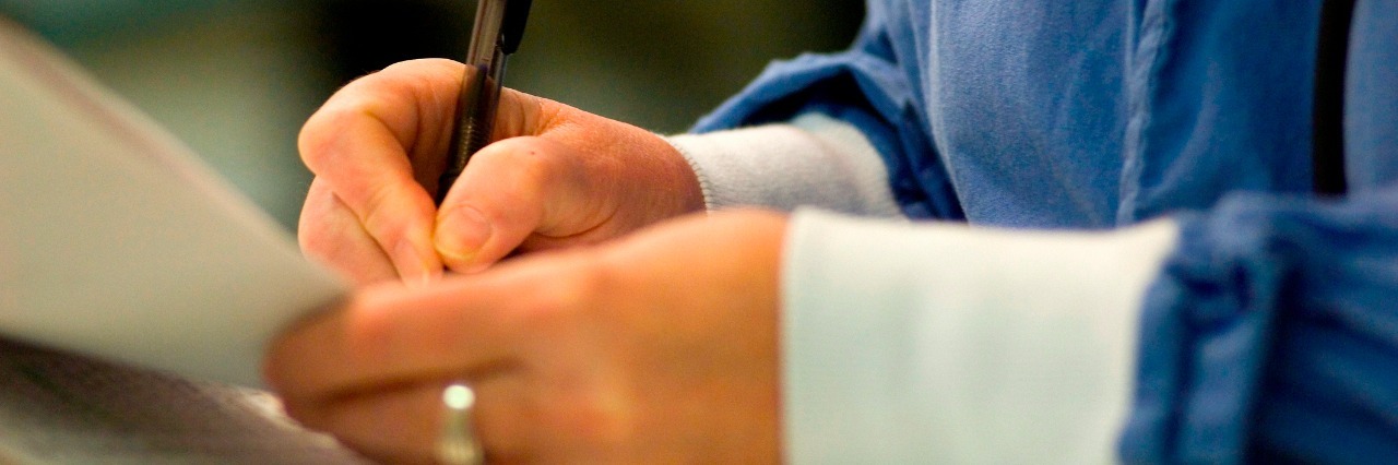 nurse writing on patient's chart