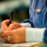 nurse writing on patient's chart