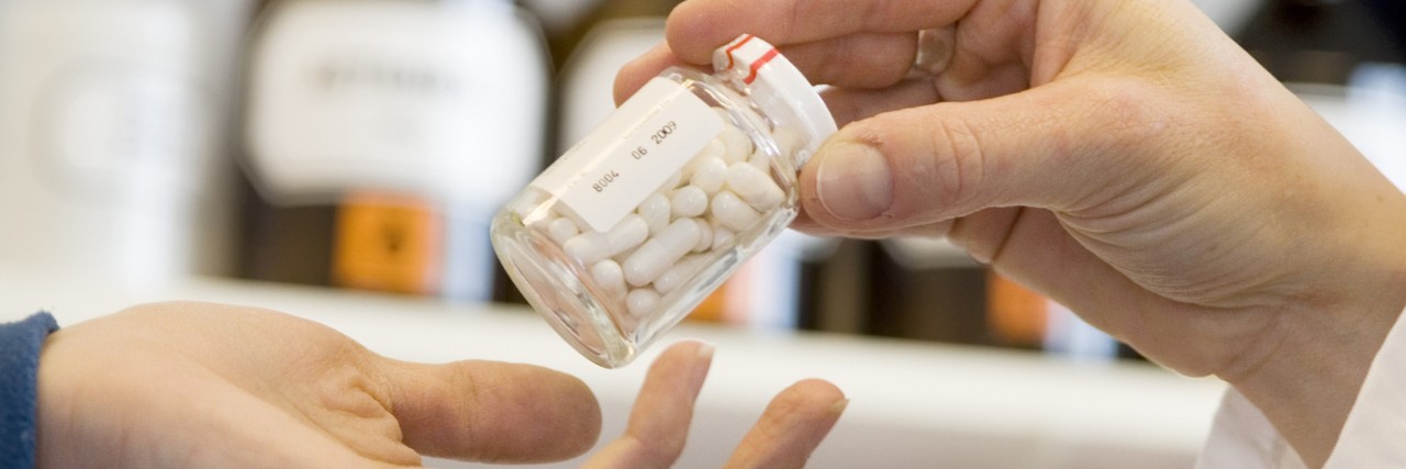 Woman Thanks Pharmacist for Help Picking Up Antidepressant Pharmacist giving pill bottle to customer