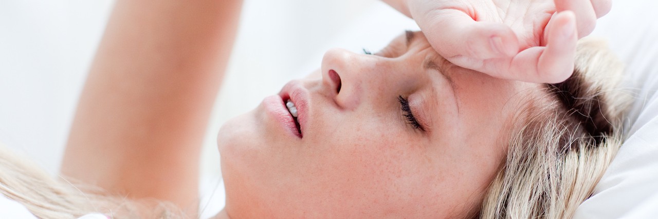 Anxiety and Panic Attacks During a Hangover A tired woman sitting in bed with her head rested on her forehead