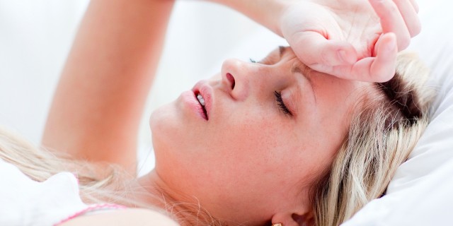 When I Realized the 'Weirdest Hangover I've Ever Had' Was Actually a Panic Attack A tired woman sitting in bed with her head rested on her forehead