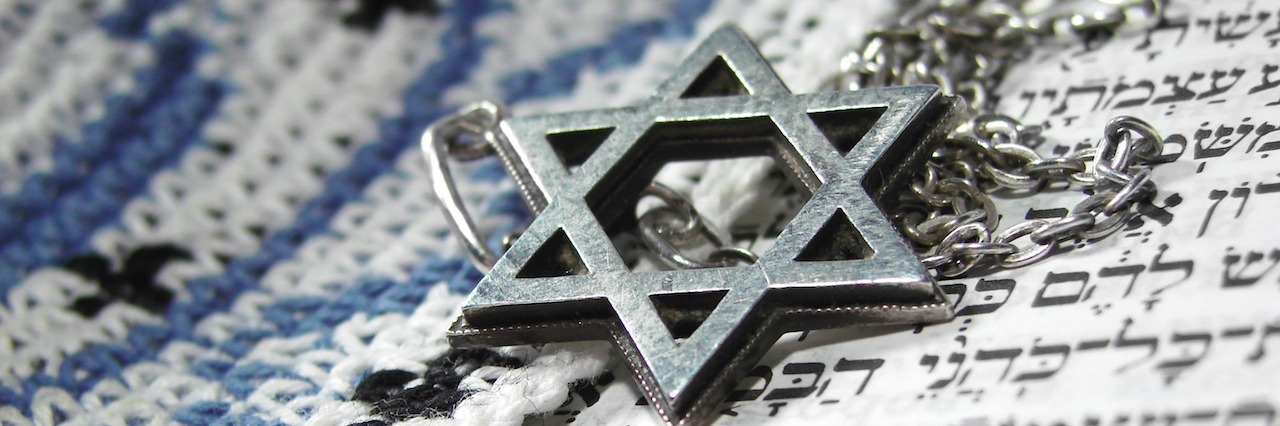 Jewish Star of David necklace laying on a paper with Hebrew letters