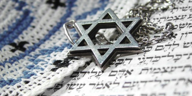 Jewish Star of David necklace laying on a paper with Hebrew letters