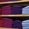 Colorful sweaters folded on shelves in clothing store