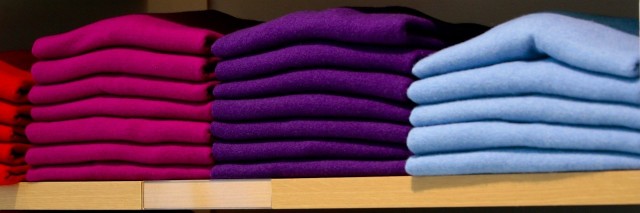 Colorful sweaters folded on shelves in clothing store