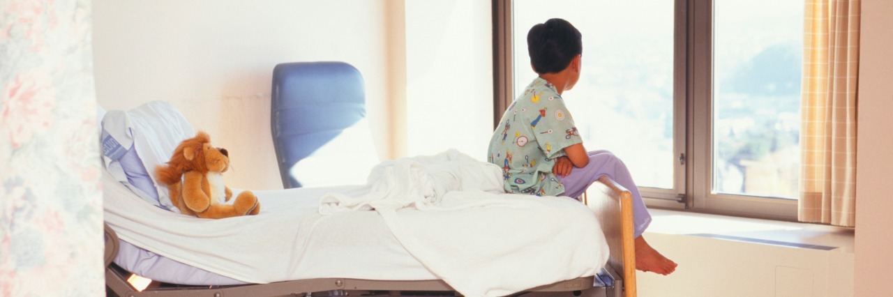 Realizing Raising a Child With Complex Needs Is a Gift Young boy (6-7) sitting on hospital bed