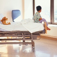 Young boy (6-7) sitting on hospital bed