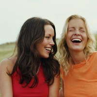 two young woman laughing, sitting outside