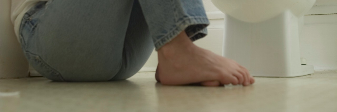 Ankylosing Spondylitis & Fibromyalgia: What I Learned About Disability woman on bathroom floor by toilet hugging knees