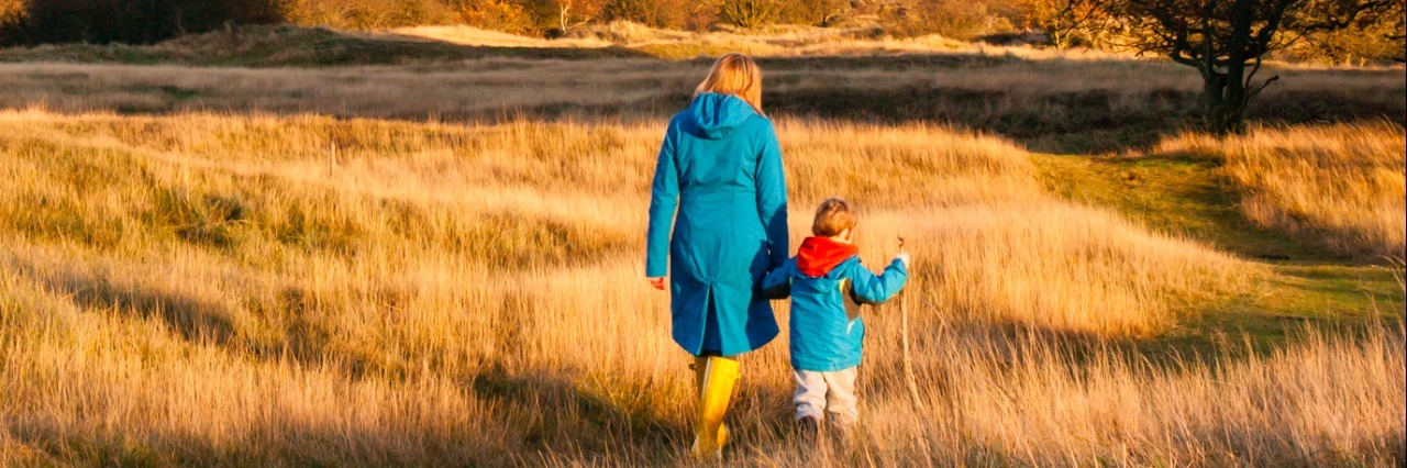 What I've Learned After My Son's Autism Diagnosis woman and boy walk hand in hand in a sunny autumn landscape